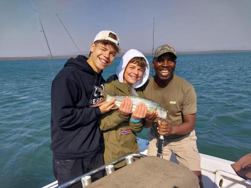 a group of three people holding a fish on a boat at Shayamoya Tiger Fishing and Game Lodge in Pongola Game Reserve