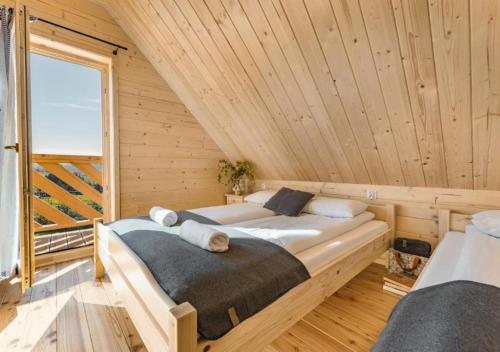 two beds in a wooden room with a window at Pienińska Przystań in Kluszkowce