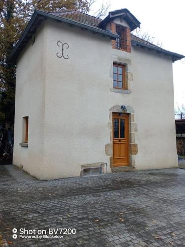 a white building with a brown door and a door istg at Maison calme in Vinzelles