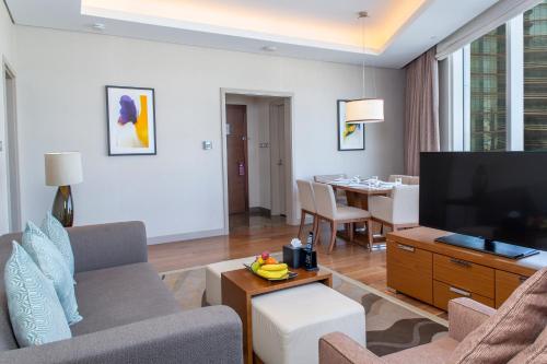 a living room with a couch and a flat screen tv at Hilton Riyadh Hotel & Residences in Riyadh