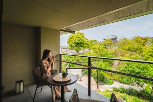 a woman sitting in a chair on a balcony talking on a cell phone at Hotel Okura Kyoto Okazaki Bettei -Age Requirement 12 over- in Kyoto