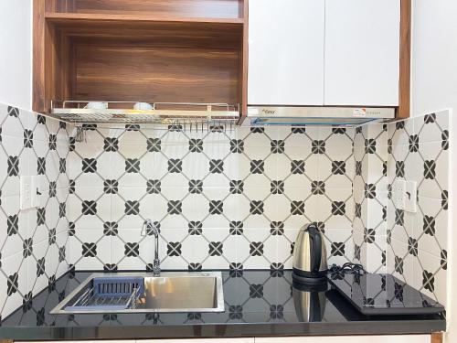 a kitchen with black and white tiles on the wall at DOME APARTMENT in Nhơn Trạch