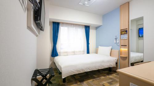 a small bedroom with a bed and a window at Toyoko Inn Gotemba Ekimae in Gotemba