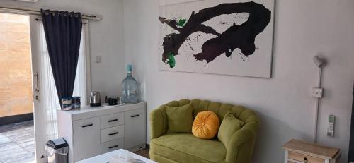 a living room with a green couch and a cabinet at Dewi Sri Guesthouse in Mataram