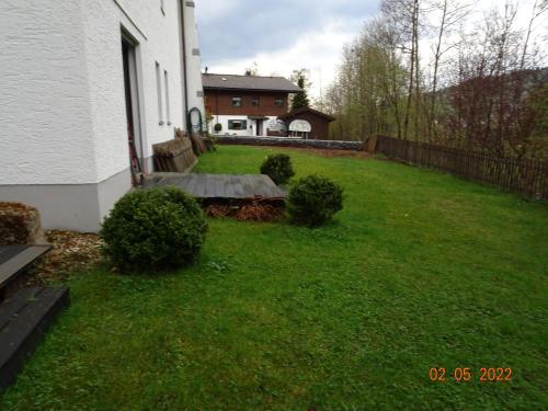 a yard with green grass and a white house at Pension Anderl in Bodenmais