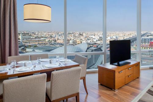 a dining room with a table with chairs and a television at Hilton Riyadh Hotel & Residences in Riyadh