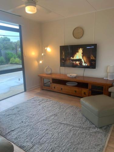 a living room with a flat screen tv on a entertainment center at Investigator Beach Breeze Apartments U1 in Kingscote