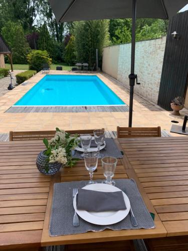 una mesa con un plato de comida junto a una piscina en Le Relais, en Arnage