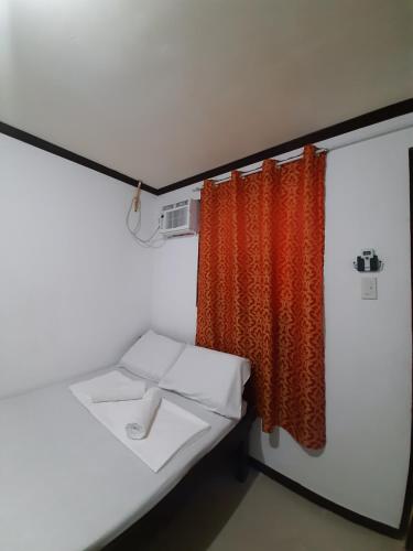 Zimmer mit orangefarbenem Vorhang und einem Bett in der Unterkunft Subangan Room 6 in Burgos