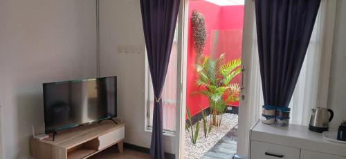 a living room with a flat screen tv next to a window at Dewi Sri Guesthouse in Mataram