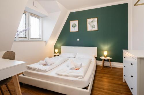 Cama blanca en habitación con pared verde en Neubau Wohnung am Eversten Holz, en Oldenburg