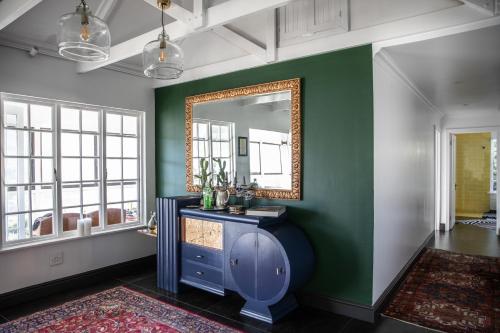 a bathroom with a mirror on a green wall at Mettahouse in Cape Town
