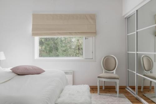 a bedroom with a bed and a window and a chair at Villa Merituuli - Charming Seafront Cottage in Porvoo
