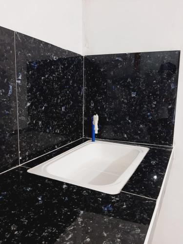 a black tiled bathroom with a white bath tub at Subangan Room 6 in Burgos