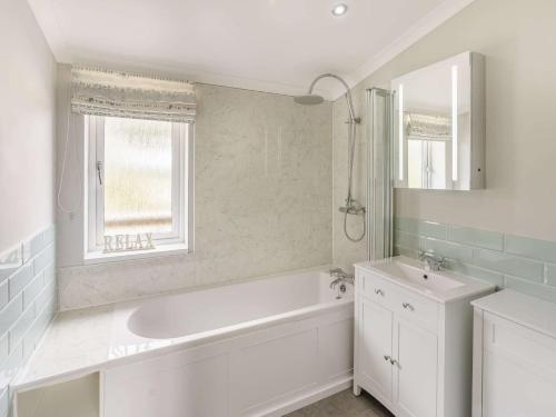 a white bathroom with a tub and a sink at 3 Bed in St Andrews 88420 in Balmullo