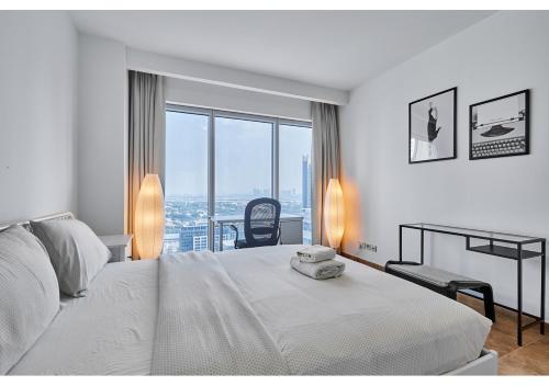 a white bedroom with a bed and a desk and window at Amazing 3BR Apartment next to Emirates Towers Metro in DIFC in Dubai