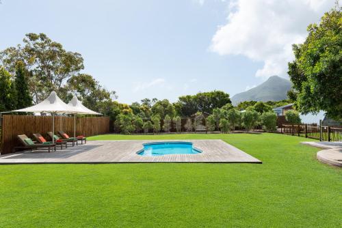 a backyard with a swimming pool and green grass at Sunset Splendour Guesthouse in Noordhoek