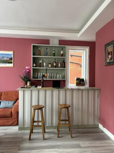 eine Bar in einem Zimmer mit rosa Wänden und 2 Hockern in der Unterkunft Boscombe Spa Hotel in Bournemouth