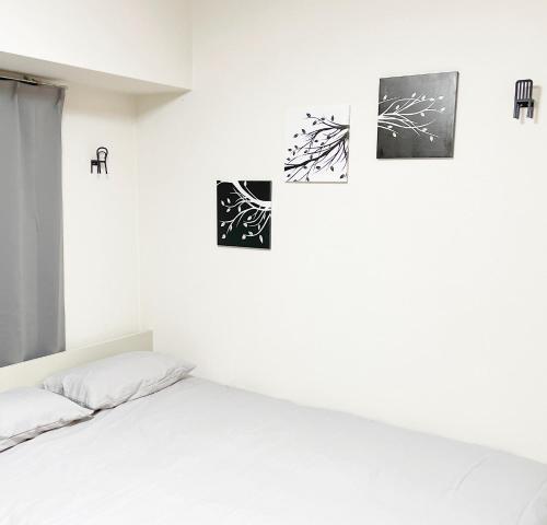 a white bedroom with a bed and pictures on the wall at 水道橋神保町 05 in Tokyo