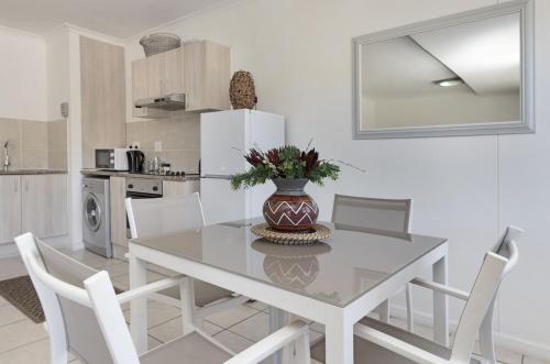 - une cuisine avec une table, des chaises et un vase fleuri dans l'établissement Azure 11, à Bloubergstrand