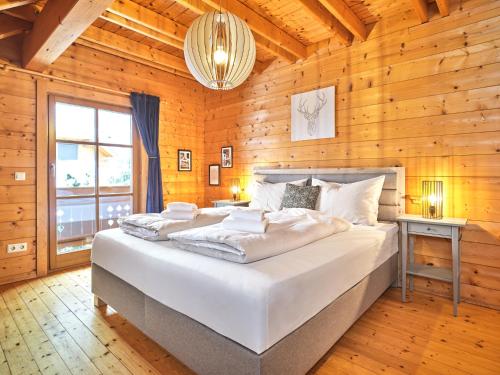 a bedroom with a large white bed in a wooden wall at Alpenglück Chalet Schladming - Dachstein by AA Holiday Homes in Sankt Martin am Grimming
