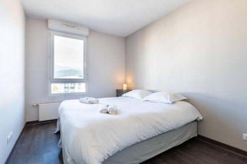 a bedroom with a large white bed with a window at Sud de Grenoble: T2 lumineux - wifi fibre - balcon in Échirolles