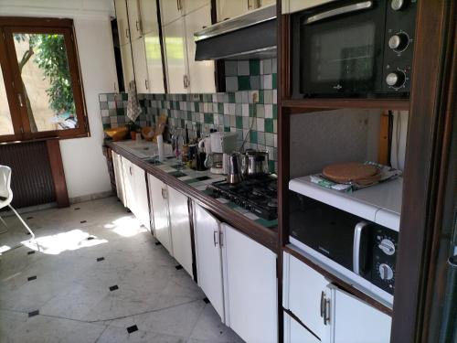 une cuisine avec des armoires blanches et un four à plaques de cuisson dans l'établissement Magnifique maison + jardin à Paris Porte des Lilas, à Bagnolet