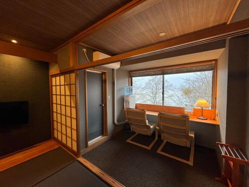 Habitación con mesa, sillas y ventana en Towadakohan Sakura en Towada