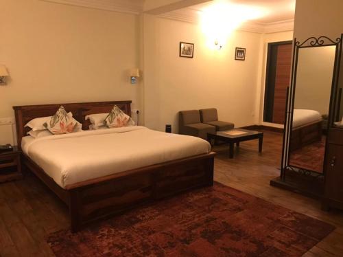 a bedroom with a bed and a chair and a mirror at The Heritage Club - Tripura Castle Hotel and Spa in Shillong