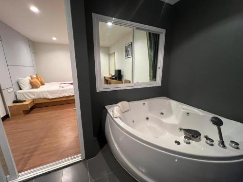 a large white tub in a bathroom with a bedroom at Zephyr Grand Hotel in Patong Beach