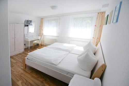 a bedroom with a white bed and a desk at Garni Hotel Bodden in Gummersbach