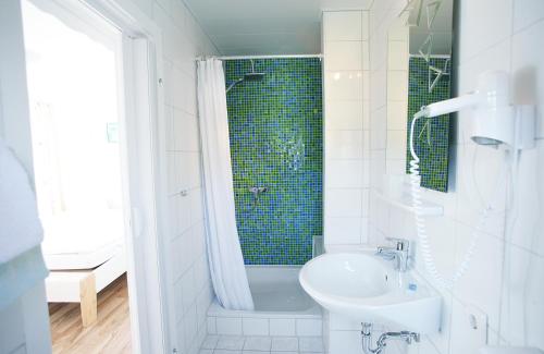a white bathroom with a sink and a shower at Garni Hotel Bodden in Gummersbach