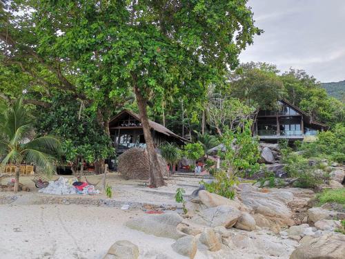 dom na plaży z drzewem i skałami w obiekcie Smile Bungalow Bottle Beach w mieście Bottle Beach