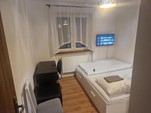 Habitación pequeña con 2 camas y escritorio. en Noclegi Budomas Budget FreeParking, Free Netflix, Free Youtube Premium, en Wroclaw