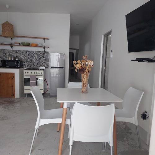 a table with white chairs and a vase of flowers on it at Karoo Retreat- Self Catering Villas and Guest House in Oudtshoorn