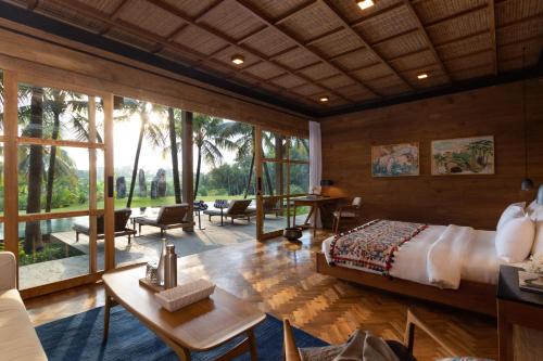 een slaapkamer met een bed en een groot raam bij Rusters Estate - Ricefield with Sunset views, Creative Spaces & Restaurant in Ubud