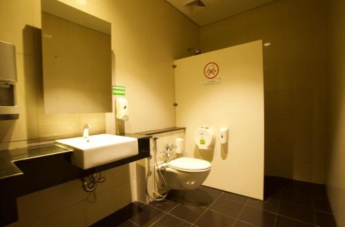 a bathroom with a toilet and a sink and a mirror at Digital Airport Hotel in Tangerang