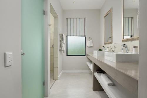 a white bathroom with two sinks and a mirror at Sunset Splendour Guesthouse in Noordhoek