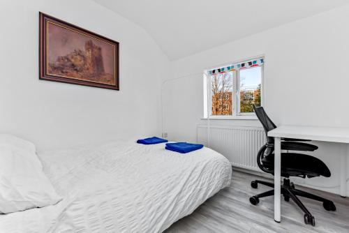 a bedroom with a bed and a desk and a computer at Family House in the Heart of Hanwell with 5 stars! in London