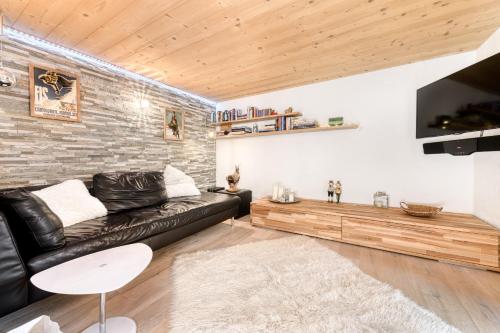 - un salon avec un canapé en cuir noir et un mur en briques dans l'établissement Ferienwohnung Zweisamkeit, à Brand