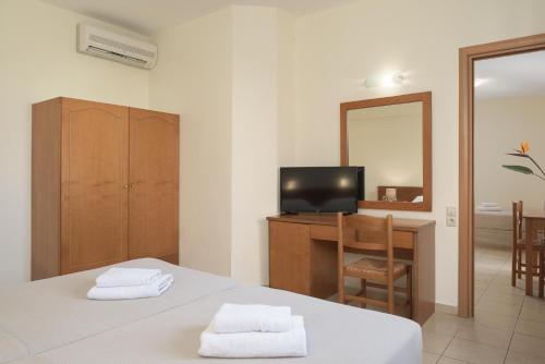 Cette chambre comprend deux lits, un bureau et un miroir. dans l'établissement Asterias Village, à Chersónissos