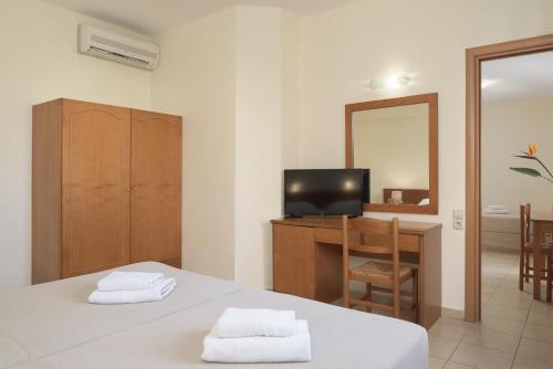 Zimmer mit 2 Betten, einem Schreibtisch und einem Spiegel in der Unterkunft Asterias Village in Hersonissos