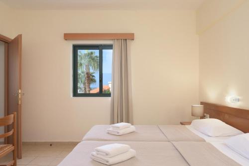 2 posti letto in una camera con 2 asciugamani bianchi di Asterias Village a Hersonissos