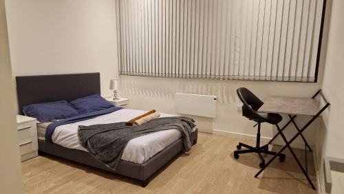 London Spacious Apartment في برينتفورد: غرفة نوم بسرير ومكتب وكرسي