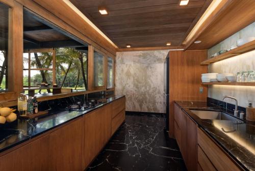 a large kitchen with wooden cabinets and a sink at Sunset Ubud Estate with Ricefield views - RUSTERS Villa Estate in Ubud