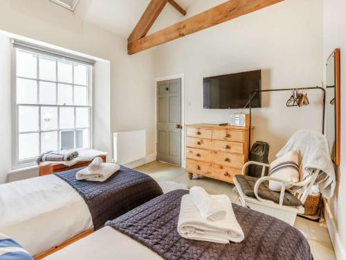 a bedroom with two beds and a tv and a dresser at 4 Bed in Appledore 88876 in Appledore