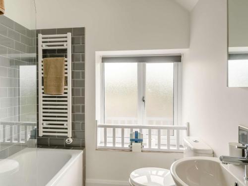 La salle de bains est pourvue d'un lavabo, d'une baignoire et d'une fenêtre. dans l'établissement 2 Bed in Tresaith 89315, à Penbryn