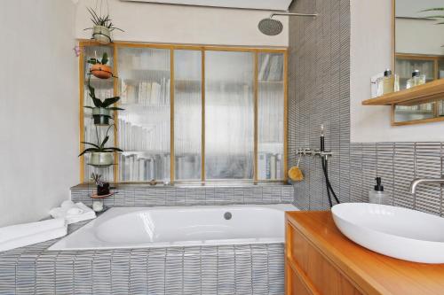 une salle de bain avec une baignoire et un lavabo dans l'établissement Appartement Familial 7 personnes -Entre Opéra et Montmartre by Weekome, à Paris