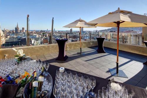 a table with wine glasses and an umbrella on a rooftop at Olivia Plaza Hotel in Barcelona