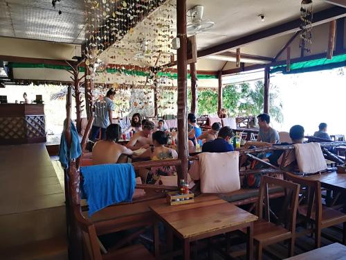 Smile Bungalow Bottle Beach في شاطئ بوتيل: مجموعة من الناس يجلسون على الطاولات في المطعم